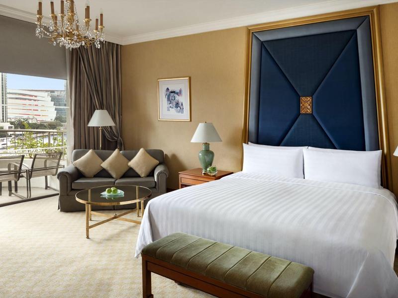 Modernes Hotelzimmer mit großem Bett, Sofa, Lampen, Balkon und elegantem Interieur.