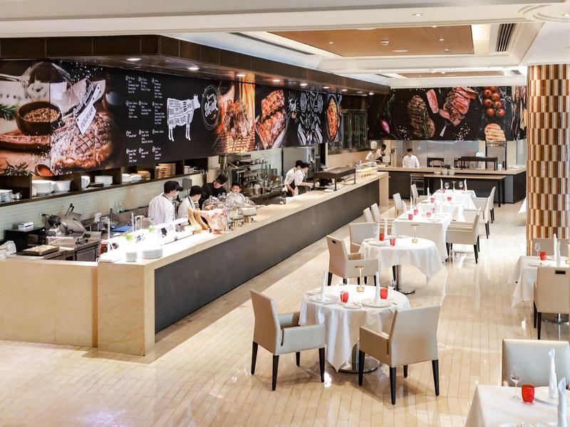 Modernes Restaurant mit weißen Tischen, grauen Stühlen und rustikaler Fleisch-Dekoration an der Wand.