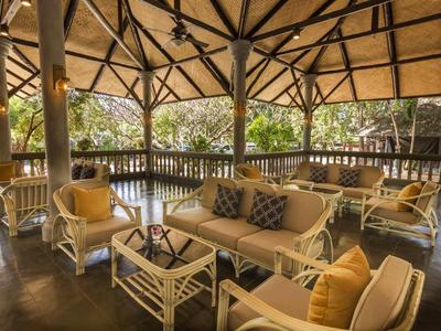 Offene Lounge mit beigen Korbsesseln, Sofas, Holztischen und Pflanzen im Hintergrund.