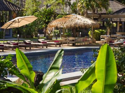 Blauer Pool mit Liegen und Sonnenschirmen in tropischem Hotelgarten