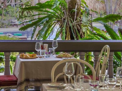 Terrassenrestaurant mit eingedeckten Tischen und grüner Pflanzenkulisse