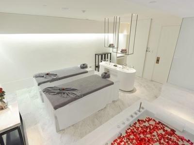 Helles Spa-Zimmer mit zwei Behandlungsliegen, Blumendekor und moderner, minimalistischer Einrichtung.