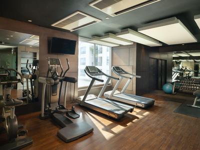 Moderner Fitnessraum mit Laufbändern, Trainingsgeräten und großen Fenstern