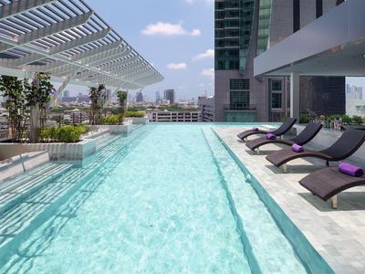 Moderner Außenpool auf einem Dach mit Liegestühlen und Blick auf die Stadt.