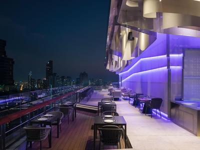 Moderne Dachterrasse mit lila Beleuchtung und Sitzgelegenheiten bei Nacht