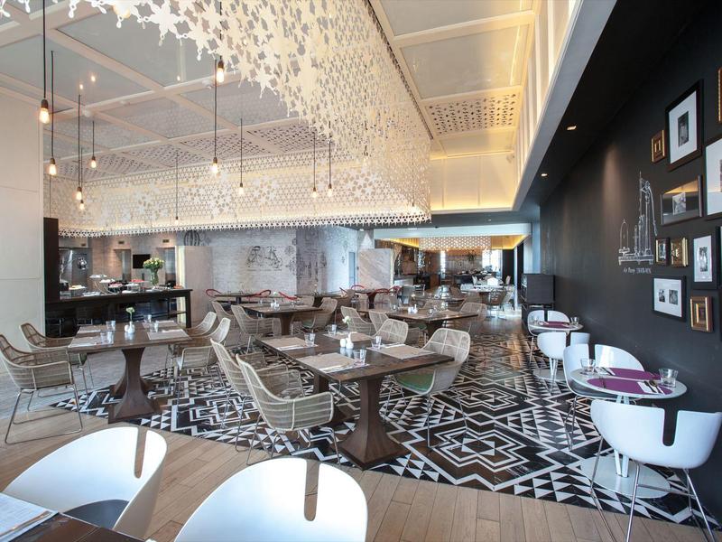 Modernes Restaurant mit elegantem Interieur, geometrischen Teppichen und stilvollen Möbeln.