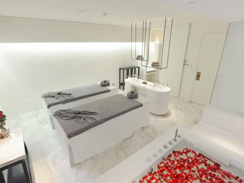 Helles Spa-Zimmer mit zwei Behandlungsliegen, Blumendekor und moderner, minimalistischer Einrichtung.