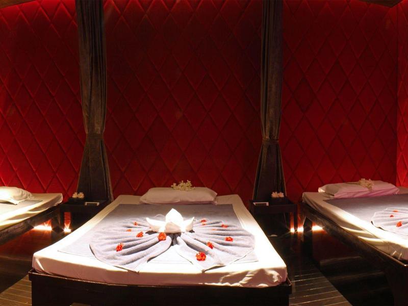 Rote Samtsitze mit dunklem Holz und weißgedeckte Tische mit Servietten und Besteck in einem Restaurant.