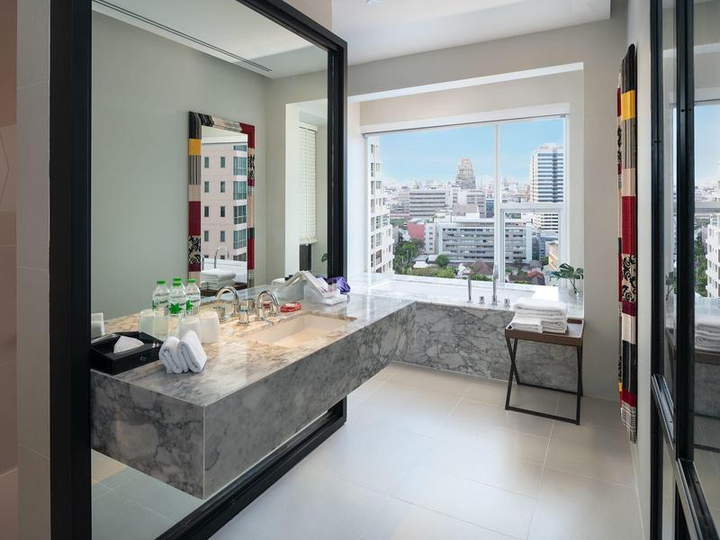 Modernes Badezimmer mit großem Spiegel, Marmorwaschbecken und Stadtblick durch großes Fenster.