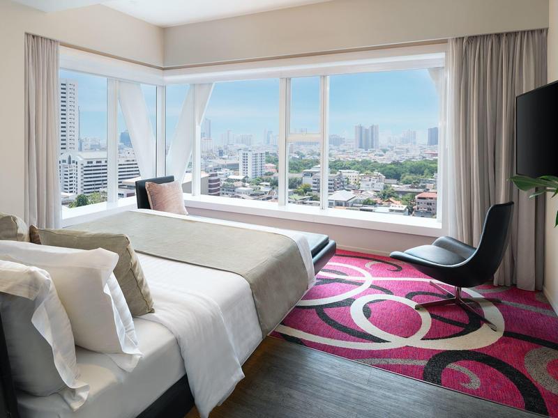 Modernes Schlafzimmer mit großem Fenster, Doppelbett, schwarz-rosa Teppich und Fernseher an der Wand.