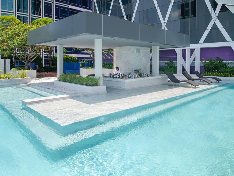 Schwimmbad mit klarem Wasser, modernem Poolbar-Pavillon und Liegestühlen im Außenbereich.