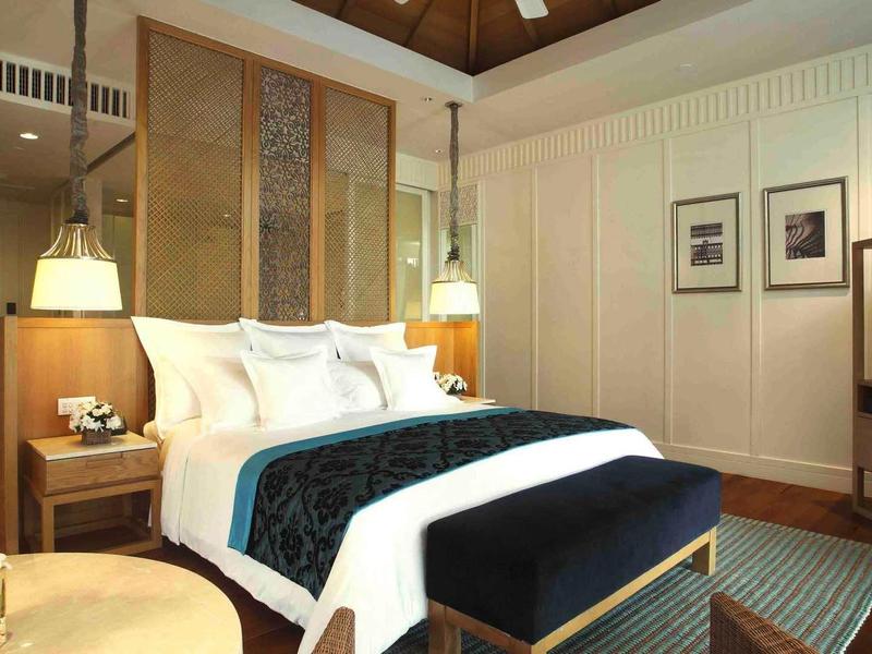 Elegant hotel room with large bed, modern lamps, and TV on wooden furniture.