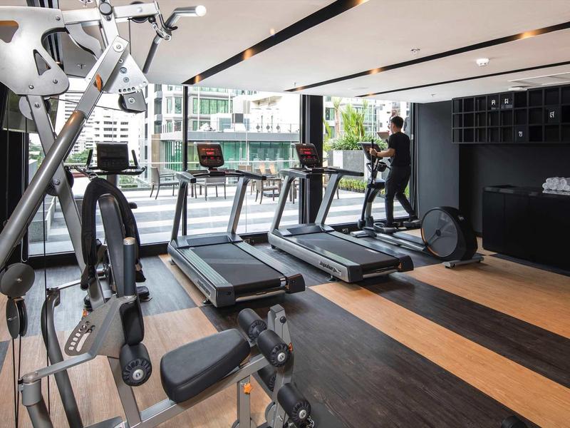 Moderner Fitnessraum mit Laufbändern, Kraftmaschinen und großem Fenster mit Stadtblick.