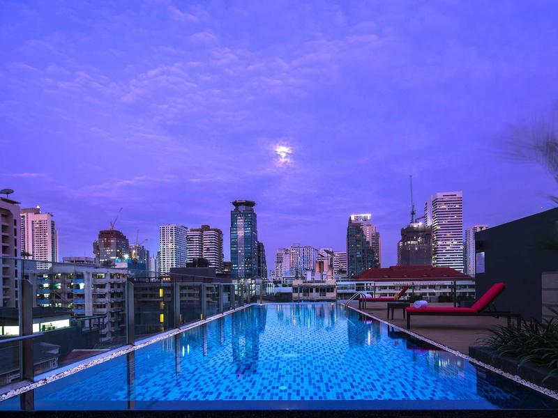 Dachpool mit Blick auf die Stadt bei Dämmerung und purpurnem Himmel