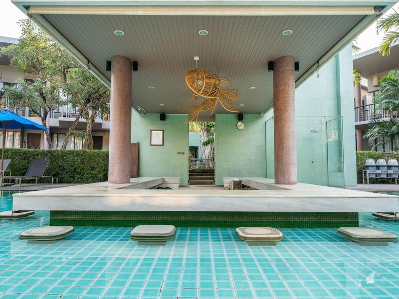 Moderner Poolbereich mit Sitzsteinen im Wasser, braunen Säulen und grünen Wänden.