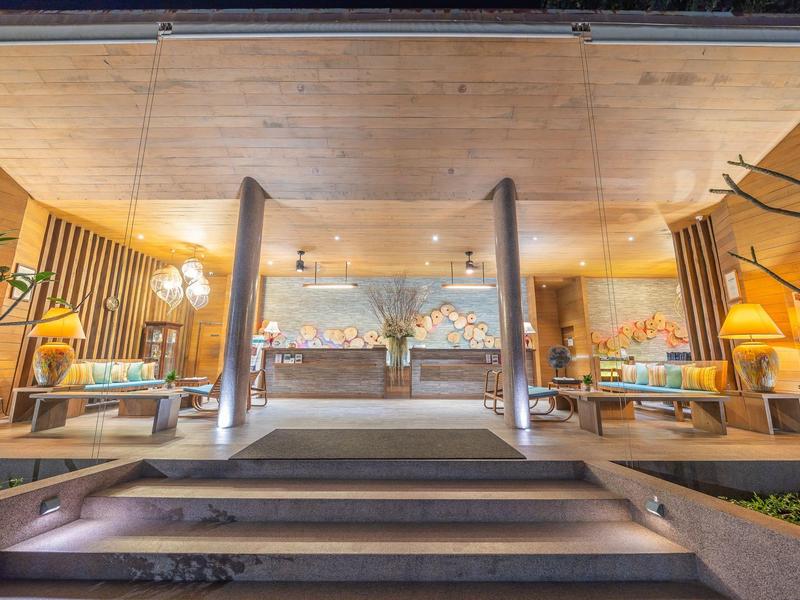 Modernes, gemütliches Wohnzimmer mit warmem Licht, Holzdecke, großen Fenstern und Pflanzen.