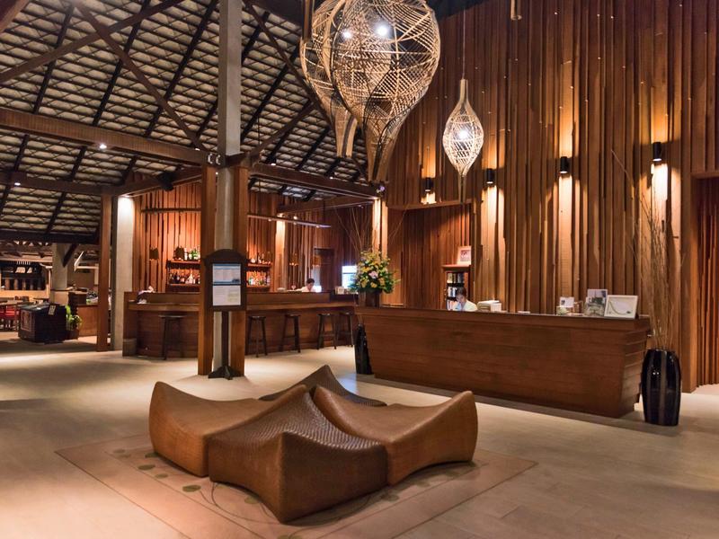 Große, warme Hotellobby mit Holzverkleidung, gemütlichen Sitzmöbeln und modernen Hängelampen.