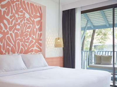 Helles Schlafzimmer mit großem weißem Bett, rosa abstraktem Wandbild und Balkon mit Aussicht.