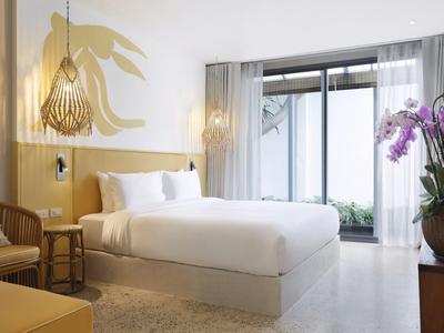 Chambre moderne et lumineuse avec grand lit, accents en bois et vue sur une terrasse.