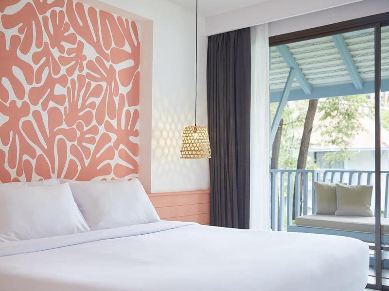 Helles Schlafzimmer mit großem weißem Bett, rosa abstraktem Wandbild und Balkon mit Aussicht.