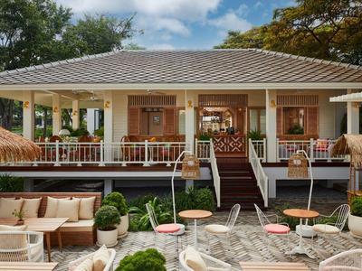Terrasse accueillante d'un hôtel avec des espaces de sièges et des plantes décoratives sous un ciel bleu.