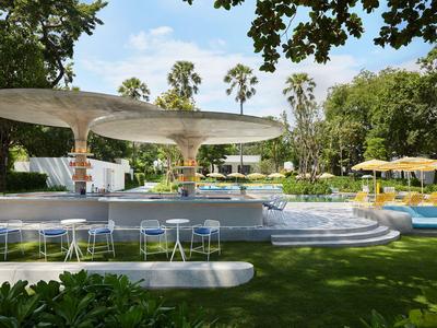 Bar extérieure moderne avec toit en forme de champignon futuriste et sièges dans un jardin verdoyant