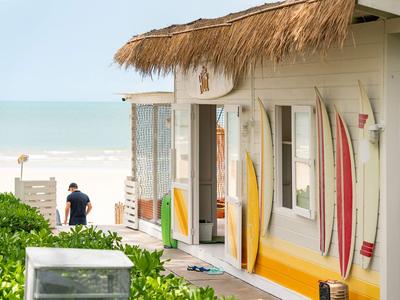 Maison de plage avec planches de surf près de l'entrée et mer en arrière-plan