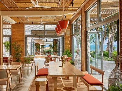 Salle à manger moderne avec mobilier en bois et grandes fenêtres donnant sur des arbres