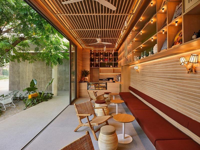 Gemütliche Terrasse mit Holzmöbeln, Pflanzen und warmen Lichtern unter Holzdecke.