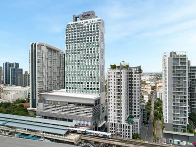 Moderne Hochhäuser in einer Stadt, klarer Himmel, breite Straße mit Verkehr im Vordergrund.