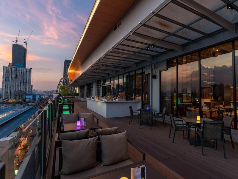 Terrasse sur le toit de l'hôtel avec espace assis et vue sur la ville au coucher du soleil.