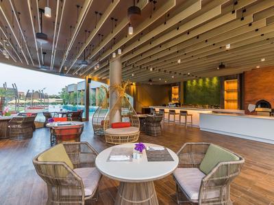 Bar d'hôtel ouverte moderne avec coin salon et vue sur la piscine.