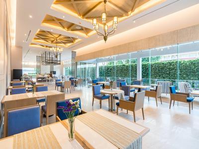 Comedor moderno y luminoso con grandes ventanas y sillas azules en un hotel.