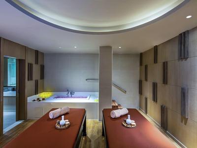 Espace bien-être moderne avec deux tables de massage et une baignoire pour la détente.