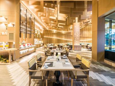 Zona de restaurante de hotel moderna y luminosa con mesas largas y sillas.