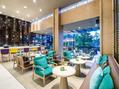 Área lounge moderna en hotel con asientos cómodos y gran ventanal.