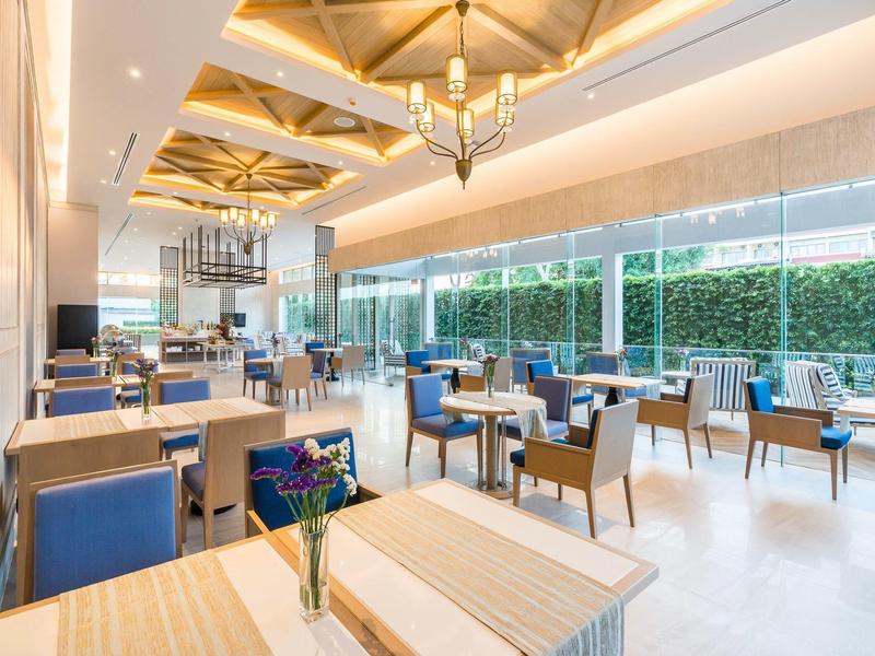 Salle à manger lumineuse et moderne avec des chaises bleues et de grandes fenêtres donnant sur l'extérieur.