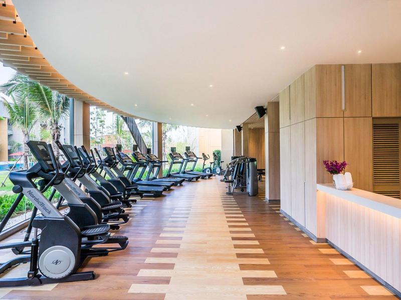 Salle de sport moderne avec plusieurs appareils d'exercice et espace lumineux et ouvert.
