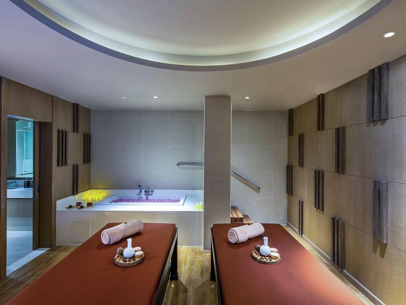 Espace bien-être moderne avec deux tables de massage et une baignoire pour la détente.