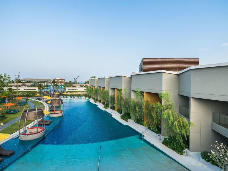 Piscine d'hôtel moderne avec transats et chambres avec terrasse sous un ciel clair