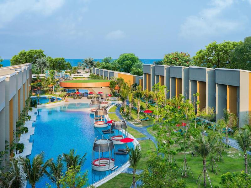 Complexe hôtelier moderne avec grande piscine et toboggans dans un environnement tropical.