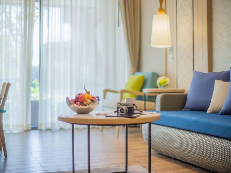 Chambre d'hôtel confortable avec canapé bleu, table d'appoint et source de lumière en plein jour.