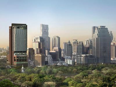Urban skyline at sunset with modern skyscrapers and green park in the foreground.
