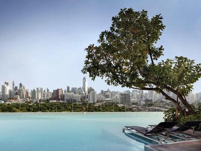 Infinity pool overlooking a city skyline and a leaning tree.