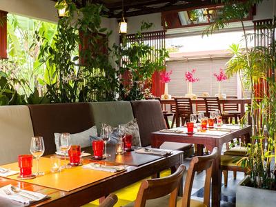 Světlá a zelená restaurace s moderními dřevěnými stoly a pohodlnými židlemi.