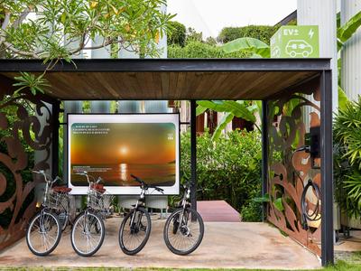 Parcheggio coperto per biciclette con quattro bici davanti a area verde dell'hotel e piante.