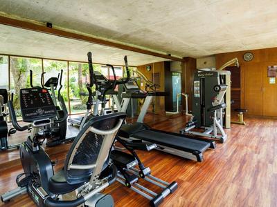 Palestra ben illuminata con varie attrezzature da ginnastica e pavimento in legno