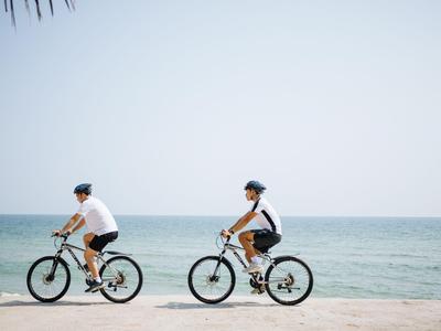 Due persone che vanno in bicicletta sulla spiaggia con vista sul mare.
