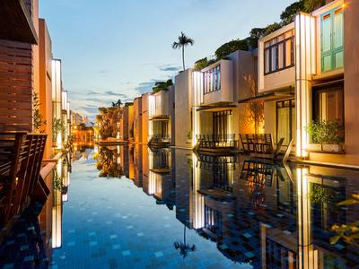 Camere d'hotel moderne con terrazze riflesse nella piscina tranquilla al tramonto.