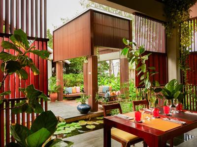 Area pranzo accogliente con decorazioni in legno e piante in un ristorante aperto e luminoso.